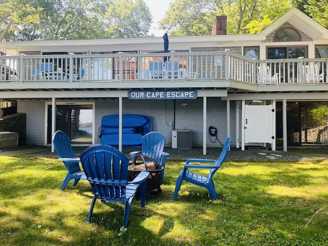 233 Hoopdole Rd, Mashpee, MA 02649 - rear view of house featuring a chimney, a fire pit, a lawn, and a wooden deck