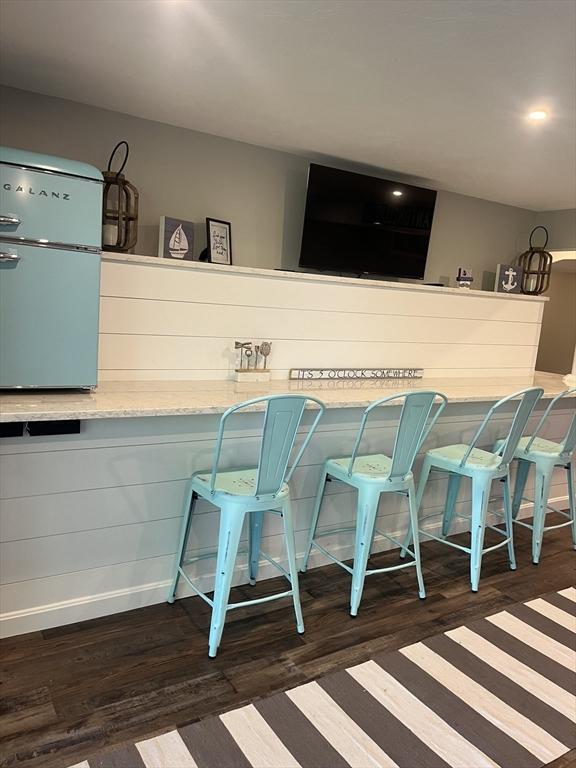 233 Hoopdole Rd, Mashpee, MA 02649 - kitchen with fridge, dark wood-style flooring, a breakfast bar area, and light stone countertops