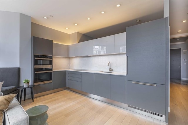 kitchen featuring light countertops, light wood-style floors, a sink, and gray cabinetry