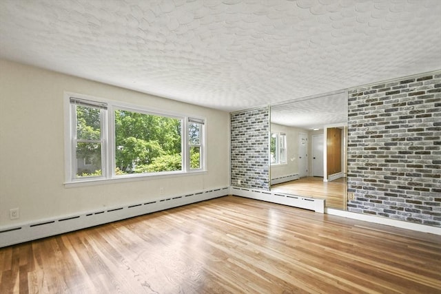 35 Woodland Rd, Leominster, MA 01453 - unfurnished room featuring wood finished floors, a textured ceiling, and a baseboard heating unit