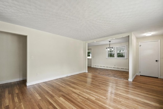35 Woodland Rd, Leominster, MA 01453 - unfurnished living room featuring a baseboard heating unit, wood finished floors, a chandelier, and a textured ceiling
