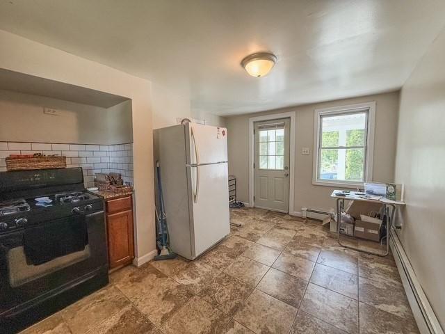68 Forest St, Lowell, MA 01851 - kitchen featuring freestanding refrigerator, gas stove, a baseboard radiator, brown cabinetry, and decorative backsplash