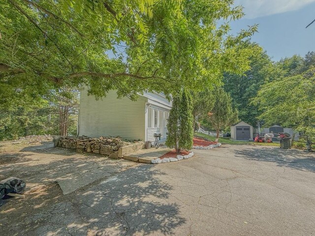68 Forest St, Lowell, MA 01851 - view of side of home featuring a storage unit and a patio