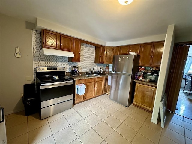 334 Howard St Unit 5, Lawrence, MA 01841 - kitchen with stainless steel appliances, under cabinet range hood, tasteful backsplash, light tile patterned flooring, and dark countertops