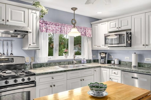 kitchen featuring pendant lighting, butcher block countertops, white cabinetry, sink, and stainless steel appliances