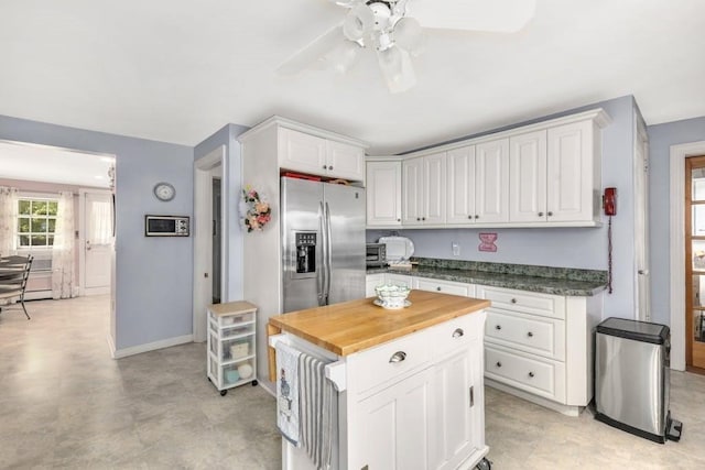 kitchen featuring wood counters, a center island, stainless steel fridge, ceiling fan, and white cabinets