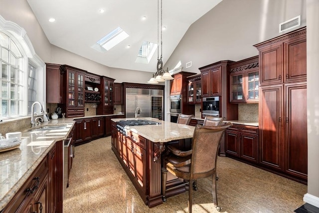 150 Horseneck Rd, Dartmouth, MA 02748 - kitchen featuring a sink, a skylight, appliances with stainless steel finishes, hanging light fixtures, and an island with sink
