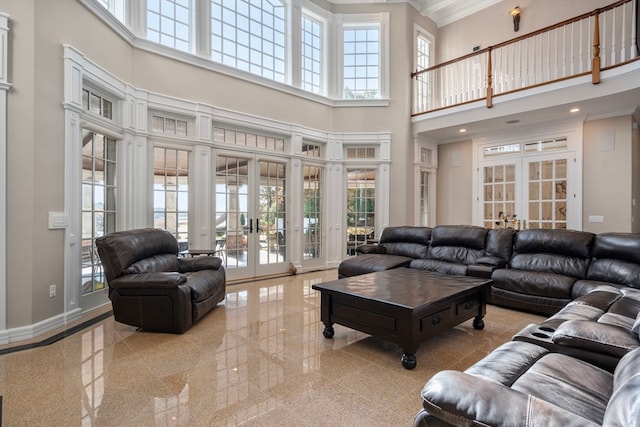 living room featuring french doors, a towering ceiling, and ornamental molding