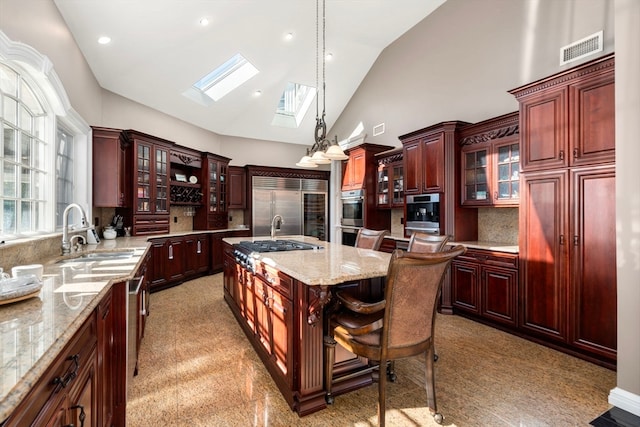 kitchen featuring a breakfast bar area, backsplash, a kitchen island with sink, pendant lighting, and sink