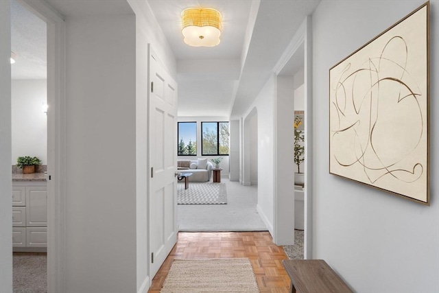 corridor with baseboards and light colored carpet