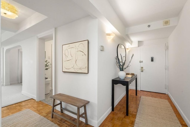 hallway with arched walkways and baseboards