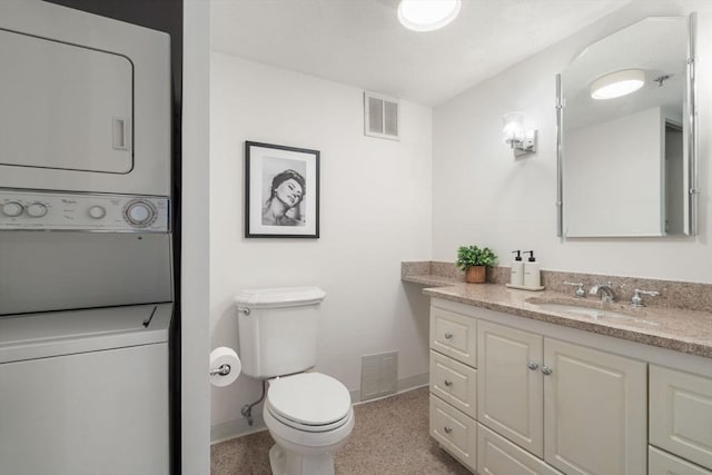 bathroom with stacked washer / drying machine, vanity, toilet, and baseboards