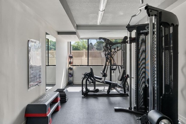 gym with a textured ceiling and baseboards