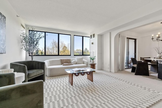 living area with arched walkways, carpet floors, a chandelier, and baseboards
