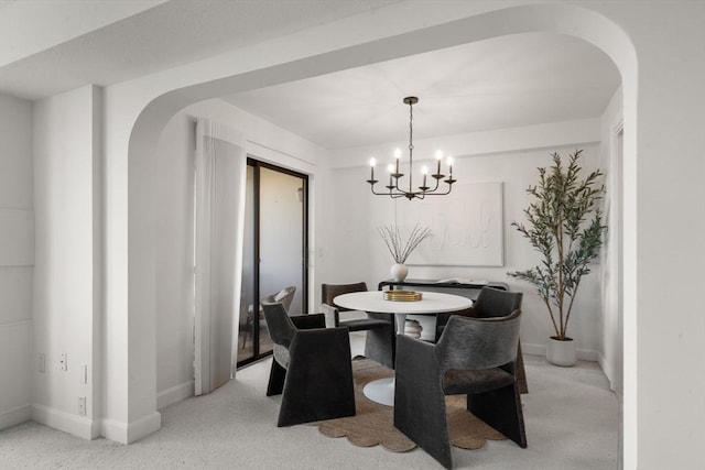 dining room with arched walkways, baseboards, a chandelier, and light colored carpet