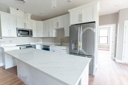 kitchen with white cabinets, sink, a kitchen island, appliances with stainless steel finishes, and light hardwood / wood-style floors