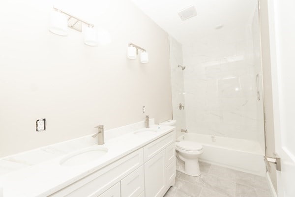 full bathroom with vanity, tiled shower / bath combo, and toilet