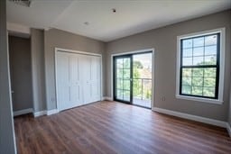 unfurnished bedroom with access to outside, dark wood-type flooring, and a closet