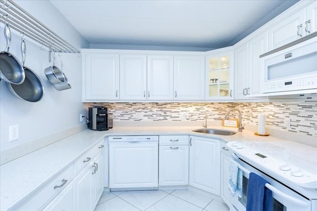 kitchen featuring white appliances, a sink, light countertops, light tile patterned flooring, and backsplash