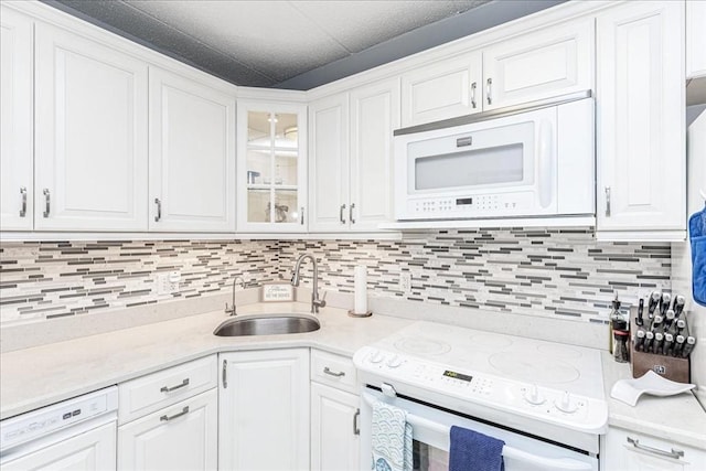 kitchen featuring white appliances, a sink, white cabinets, and tasteful backsplash