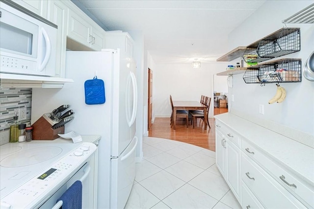 kitchen featuring white microwave, light countertops, light tile patterned flooring, and electric stove
