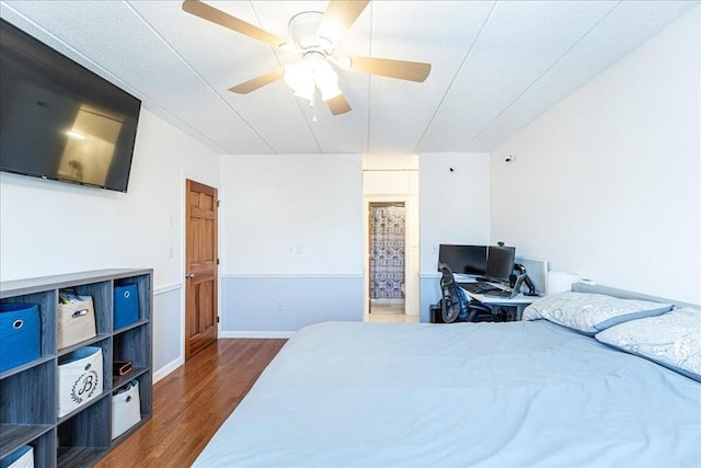 bedroom with wood finished floors, ceiling fan, ensuite bath, and baseboards