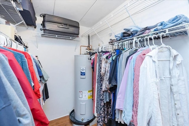 spacious closet with electric water heater and wood finished floors