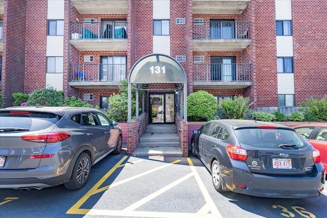 view of exterior entry with brick siding and uncovered parking