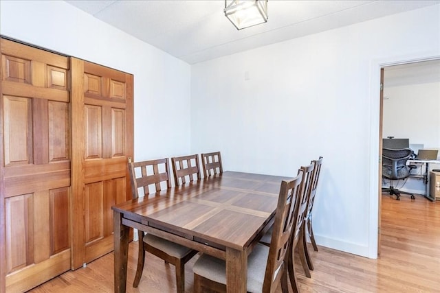 dining space with light wood-style flooring and baseboards