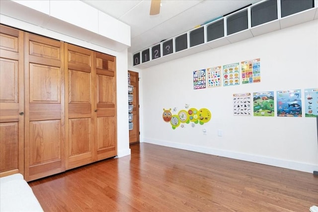 unfurnished bedroom featuring wood finished floors, baseboards, a closet, and ceiling fan