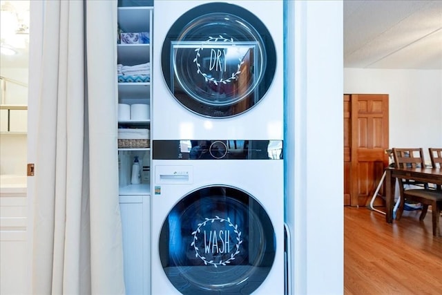 washroom featuring stacked washer and clothes dryer and wood finished floors