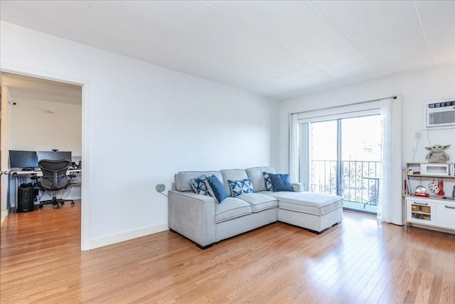 living room featuring light wood-type flooring, a desk, baseboards, and a wall mounted AC