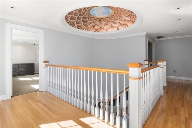 corridor featuring baseboards, an upstairs landing, ornamental molding, and hardwood / wood-style flooring