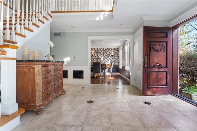 entrance foyer featuring crown molding, visible vents, wainscoting, and a wealth of natural light