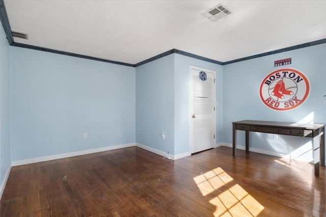 spare room with visible vents, baseboards, crown molding, and wood finished floors