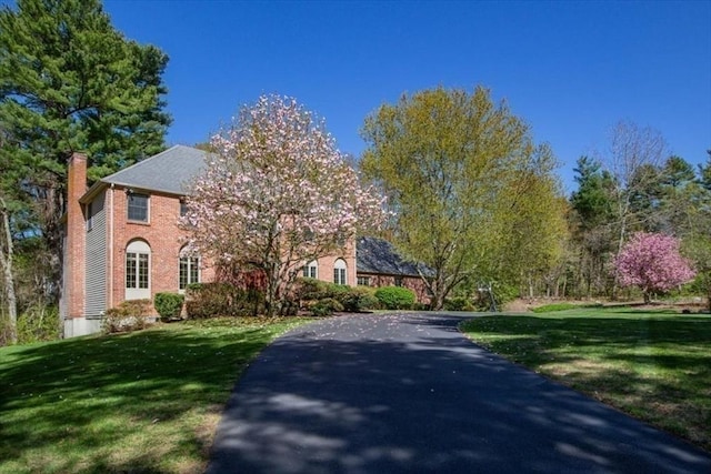 view of front of home featuring a chimney, a front lawn, and brick siding