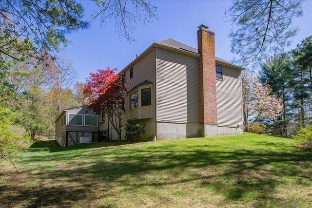 view of home's exterior featuring a lawn and a chimney