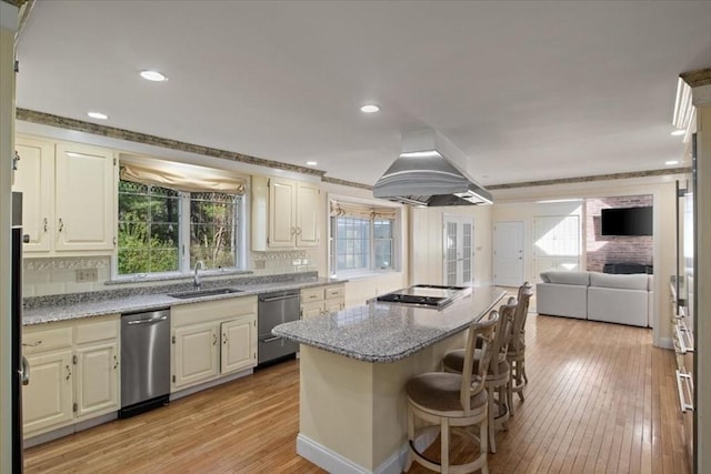 kitchen featuring light stone countertops, a center island, island exhaust hood, a sink, and stainless steel appliances