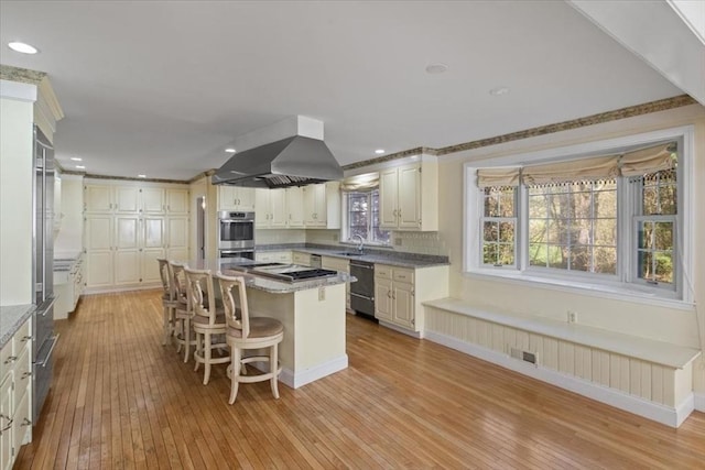 kitchen featuring appliances with stainless steel finishes, ventilation hood, light wood finished floors, a center island, and visible vents