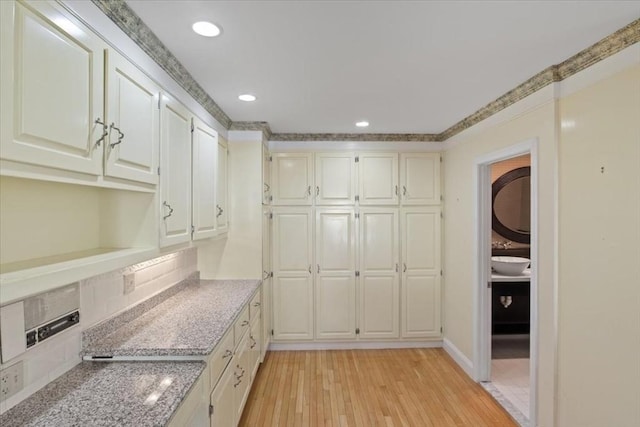 interior space featuring decorative backsplash, light stone countertops, recessed lighting, white cabinetry, and light wood-style flooring