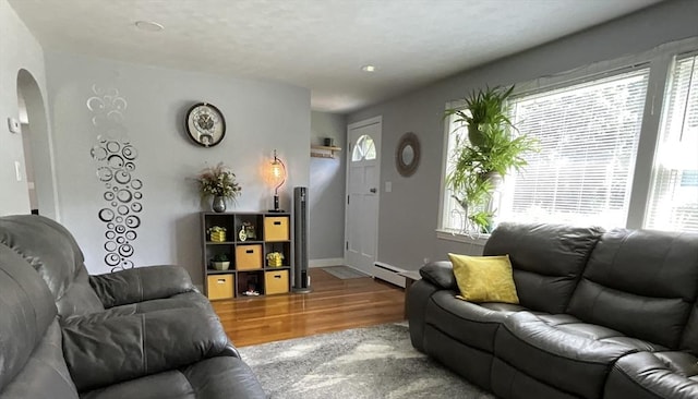 412 Worcester St, West Boylston, MA 01583 - living area with arched walkways, wood finished floors, plenty of natural light, and a baseboard heating unit