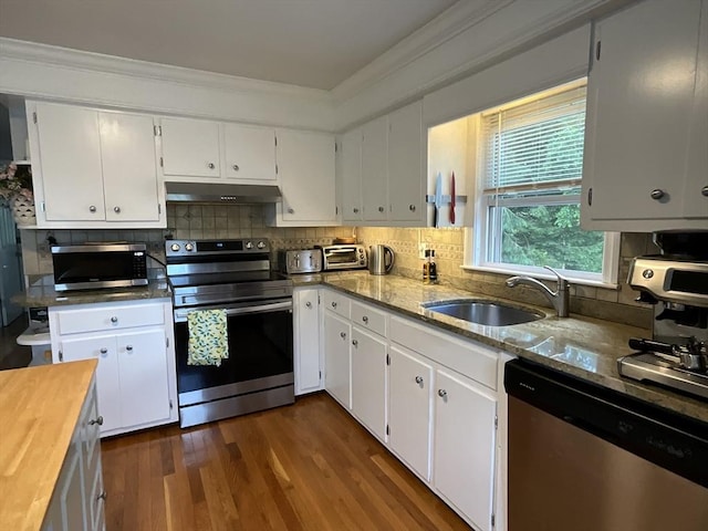 412 Worcester St, West Boylston, MA 01583 - kitchen with appliances with stainless steel finishes, under cabinet range hood, white cabinets, dark wood-style flooring, and ornamental molding
