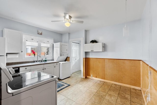130 Francis St, Everett, MA 02149 - kitchen with electric range, stacked washing machine and dryer, a ceiling fan, wainscoting, and white cabinetry