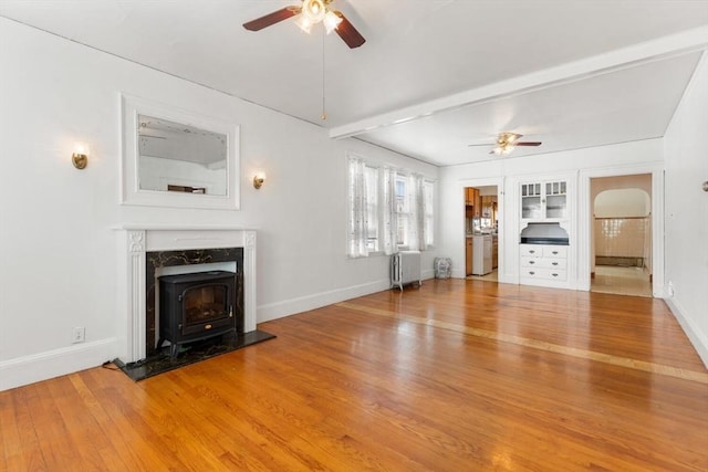 130 Francis St, Everett, MA 02149 - unfurnished living room featuring radiator, ceiling fan, a wood stove, and wood finished floors