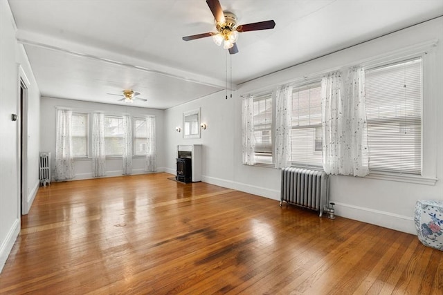 130 Francis St, Everett, MA 02149 - unfurnished living room with radiator heating unit, a wood stove, a ceiling fan, and hardwood / wood-style flooring