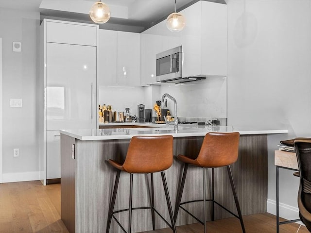 100 Shawmut Ave Unit 709, Boston, MA 02118 - kitchen featuring stainless steel microwave, modern cabinets, white cabinetry, and light wood-type flooring
