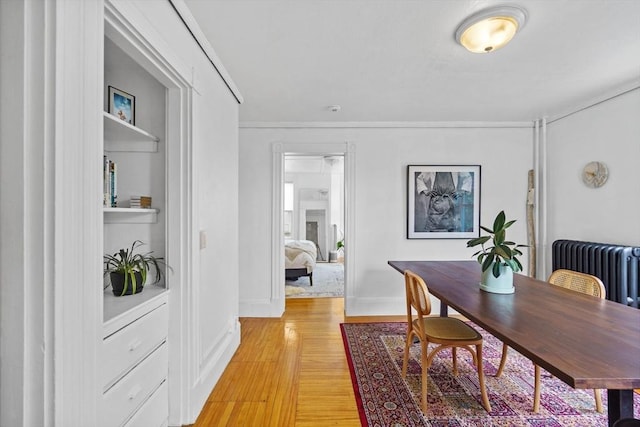 dining room featuring light wood-style flooring, baseboards, and radiator heating unit