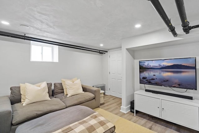 living room featuring wood finished floors, baseboards, radiator heating unit, and recessed lighting