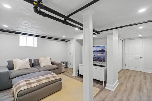 living room featuring light wood-style flooring, baseboards, radiator heating unit, and recessed lighting