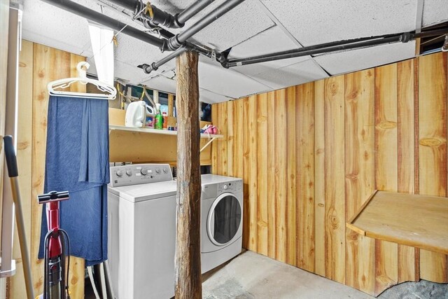 washroom featuring washer and clothes dryer, laundry area, and wooden walls